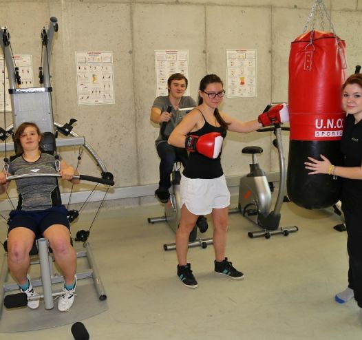 Jugendliche im Fitnessraum beim Kraft-Training und Boxen