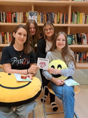 Mehrere Mädchen mit Smiley-Kissen in der Schul-Bibliothek